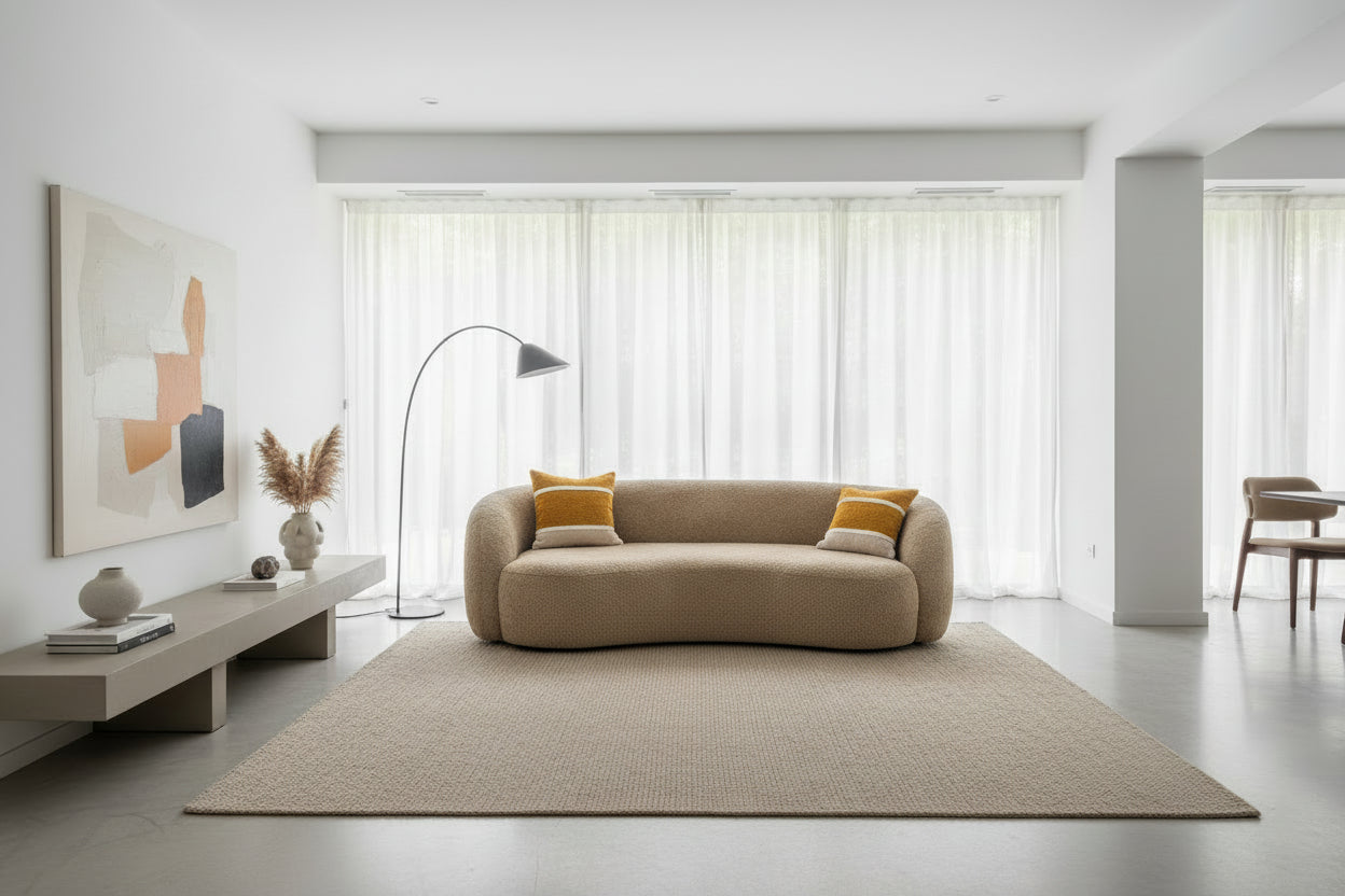 Beige curved sofa against a neutral wall.